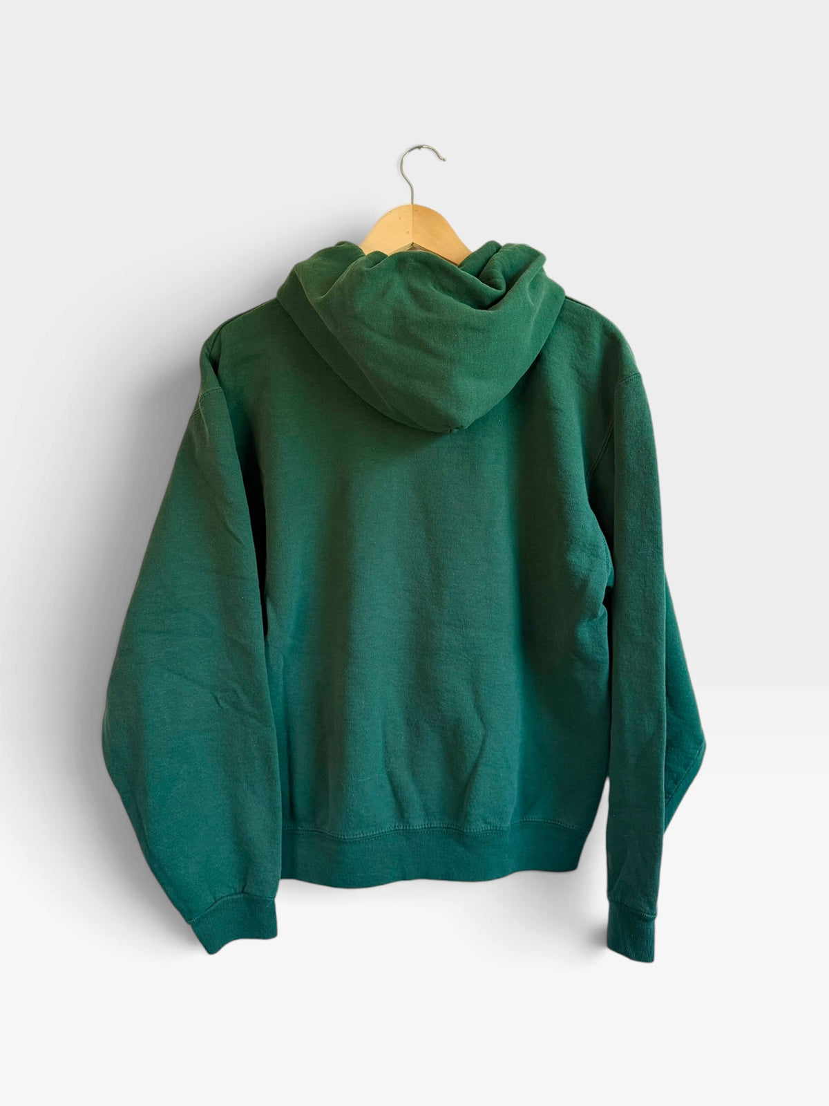 225 Threadz forest green cotton-blend pullover hoodie viewed from the back hanging on a wooden hanger