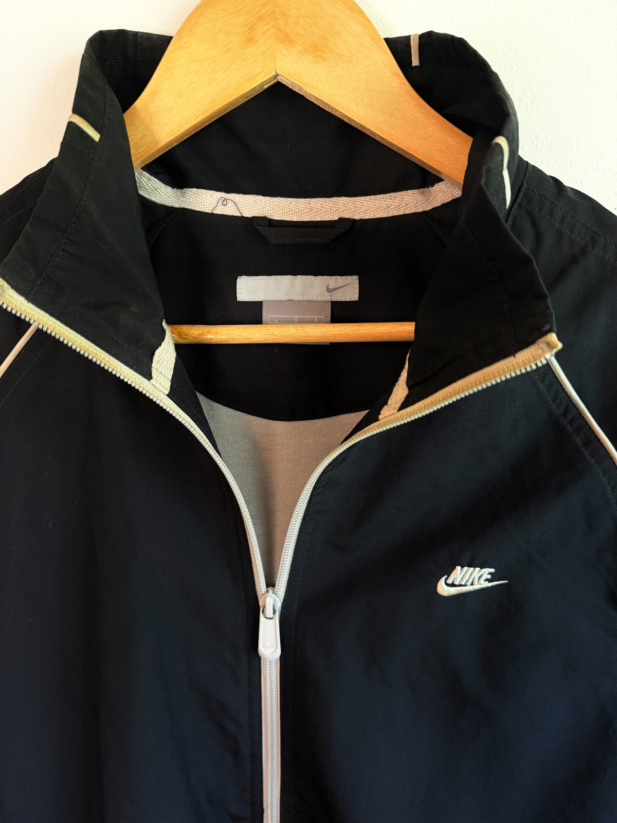 225 Threadz black Nike full-zip athletic windbreaker jacket with white piping and embroidered logo on a wood hanger