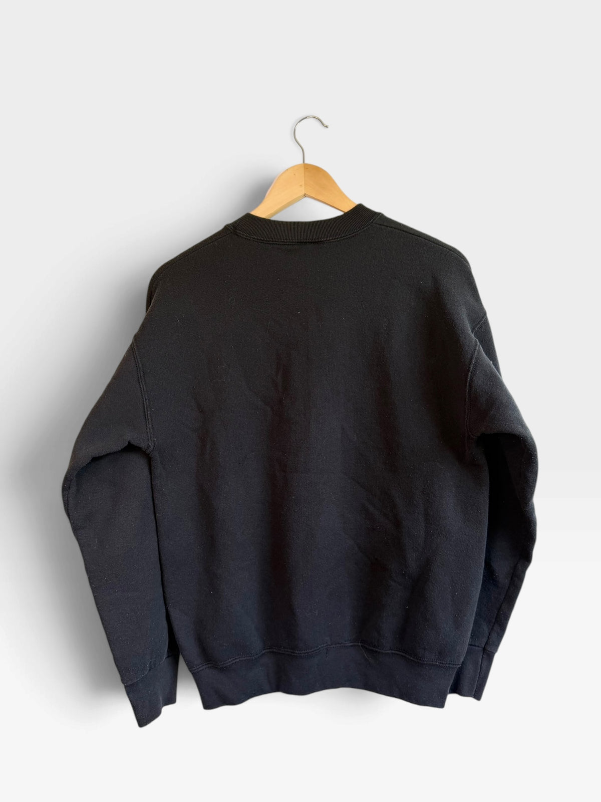 225 Threadz black crewneck sweatshirt hanging on a wooden hanger, showing the plain back view.