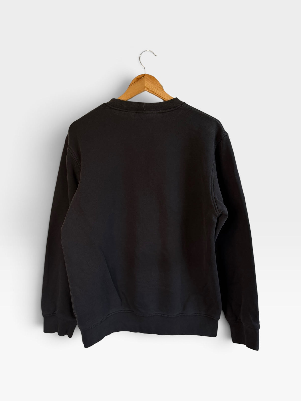 225 Threadz black Nike crewneck sweatshirt hanging on a wooden hanger against a plain white background