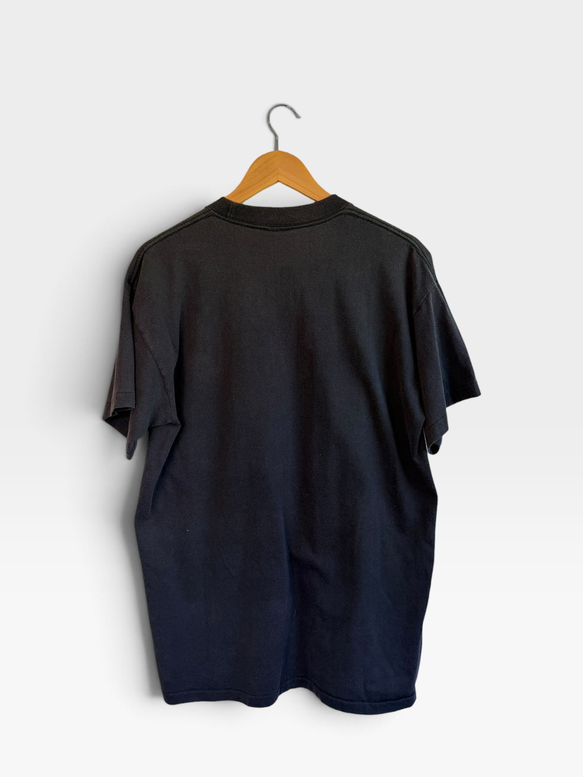Back view of a plain black 225 Threadz vintage-style cotton crew neck t-shirt hanging on a wooden hanger.