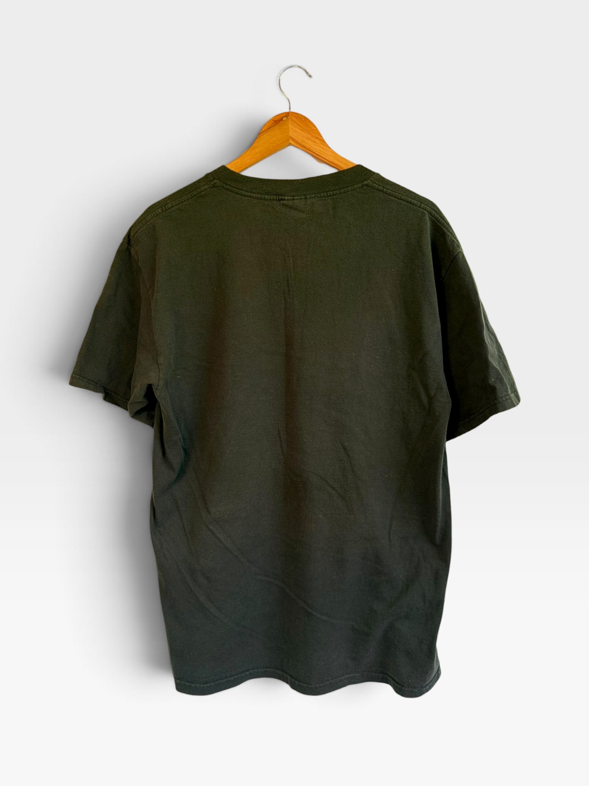 Back view of a plain black vintage 225 Threadz cotton crewneck t-shirt hanging on a wooden hanger against a white wall.