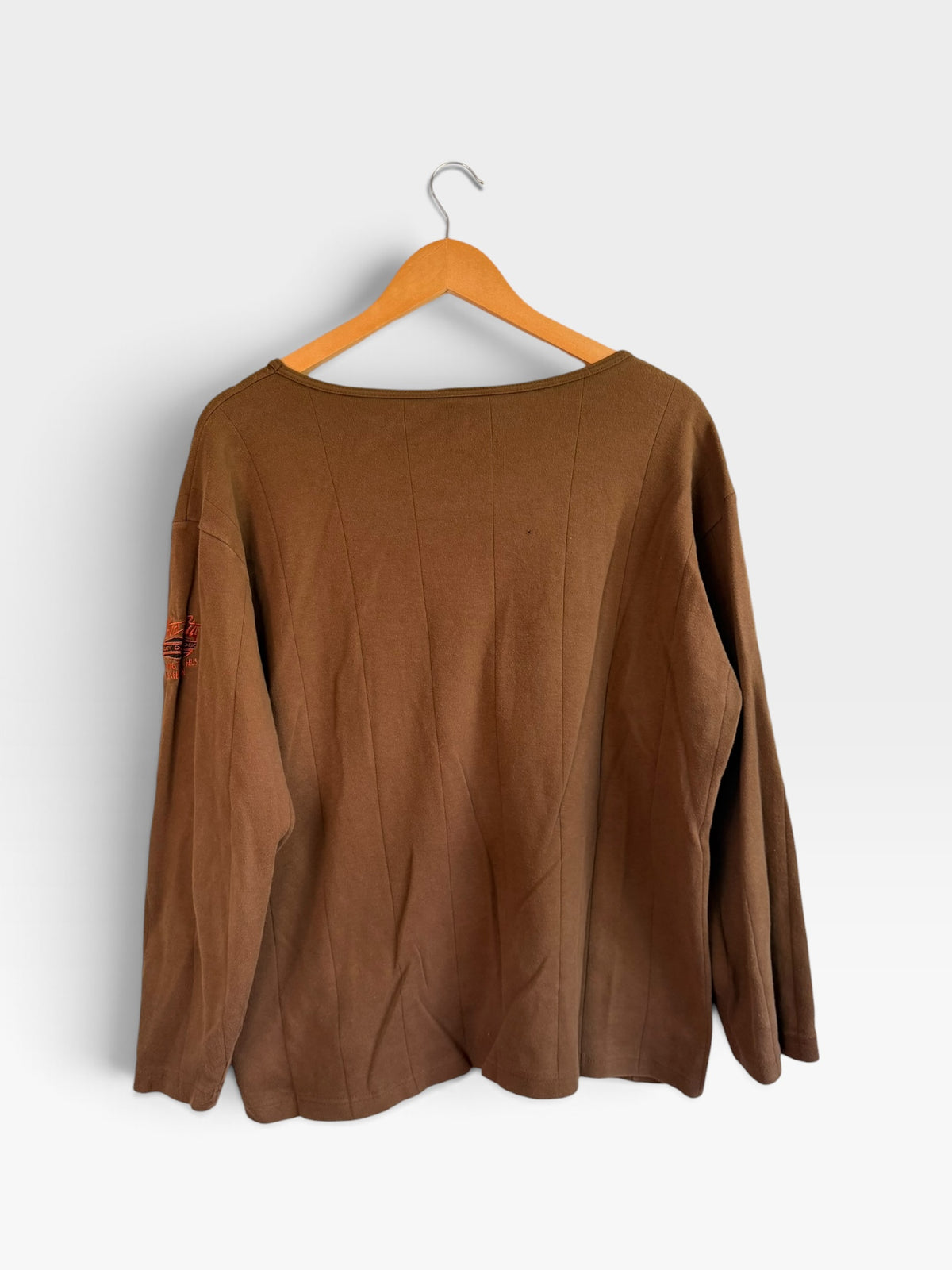 225 Threadz brown long sleeve crewneck shirt with vertical paneling and embroidered sleeve detail on a hanger