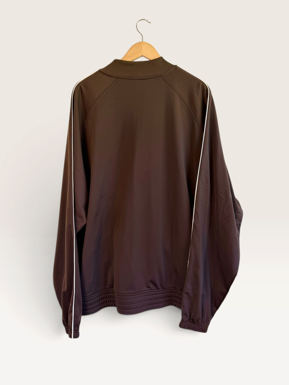 Back view of a 225 Threadz vintage style brown track jacket with white piping detail on a wooden hanger.