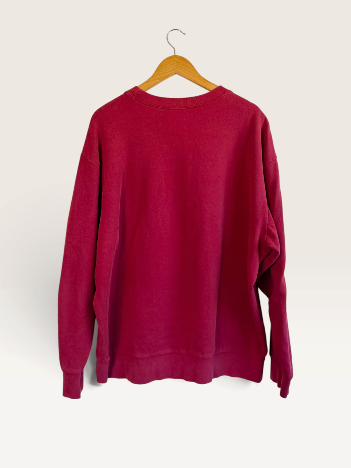 Back view of a 225 Threadz vintage Nike burgundy crewneck sweatshirt hanging on a wooden hanger against a plain wall.