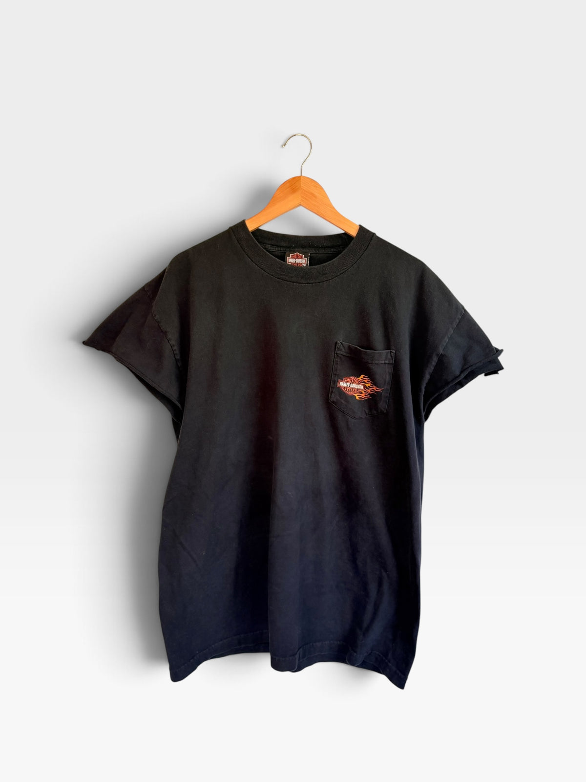 225 Threadz black Harley-Davidson cotton pocket t-shirt with flame logo on chest, hanging on a wooden hanger.