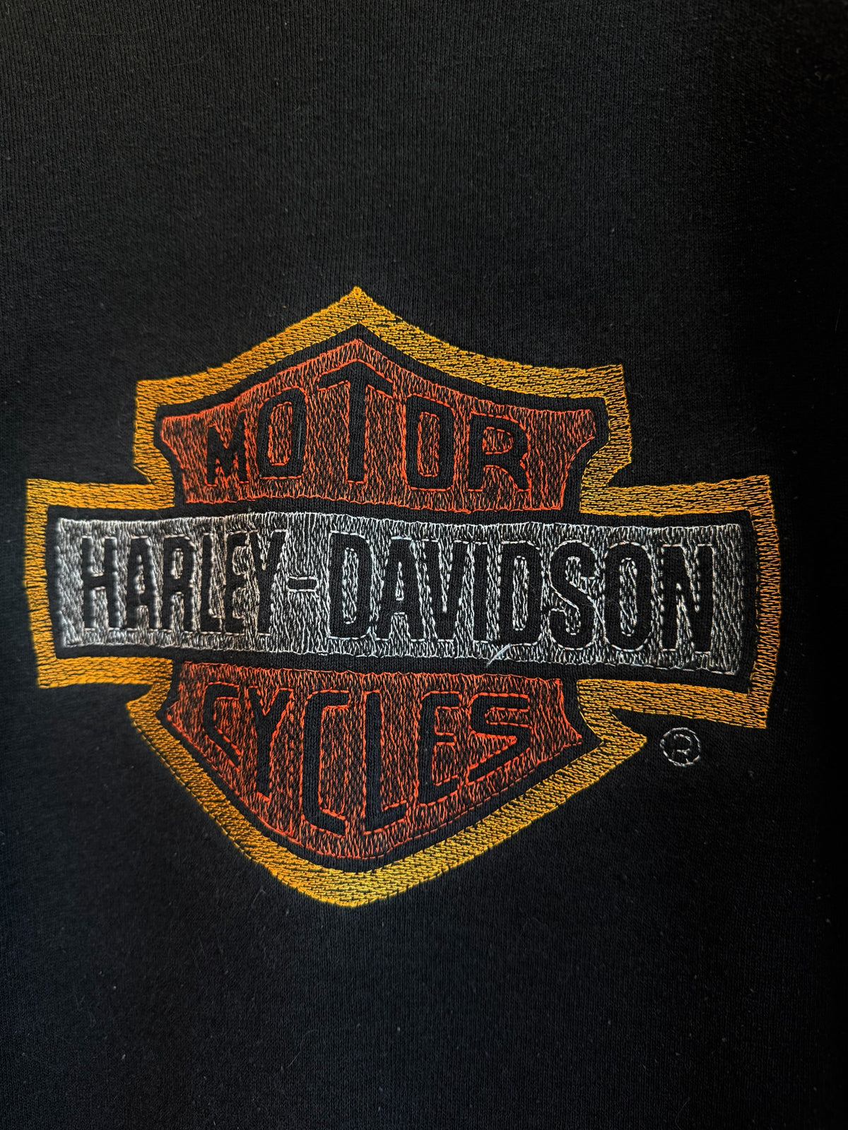 225 Threadz black crewneck sweatshirt featuring an embroidered orange, yellow, and grey Harley-Davidson logo.