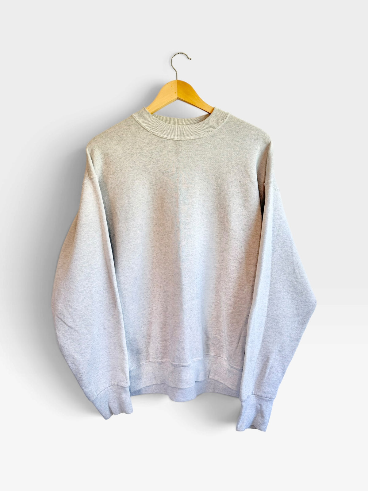 225 Threadz heather grey crewneck sweatshirt with ribbed cuffs and hem hanging on a wooden hanger