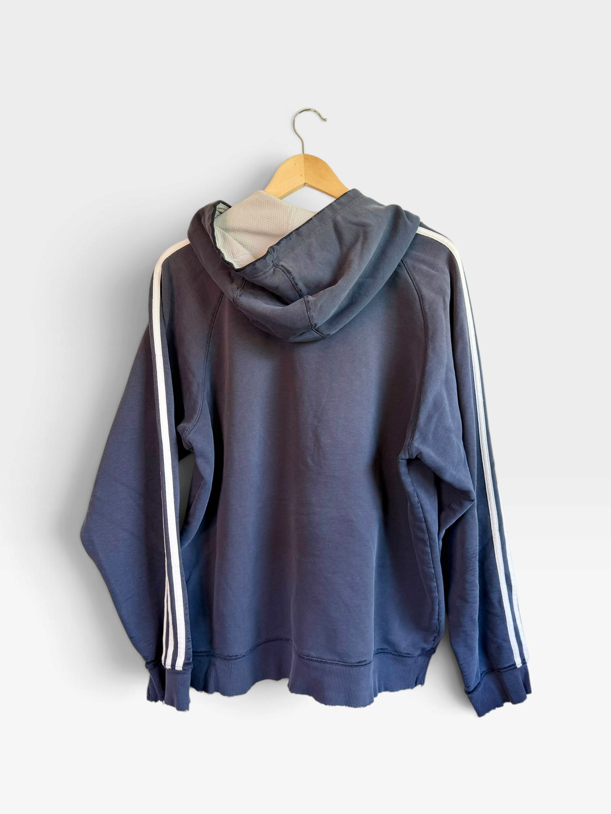 225 Threadz navy blue adidas pullover hoodie with white three-stripe sleeve detailing hanging on a wooden hanger