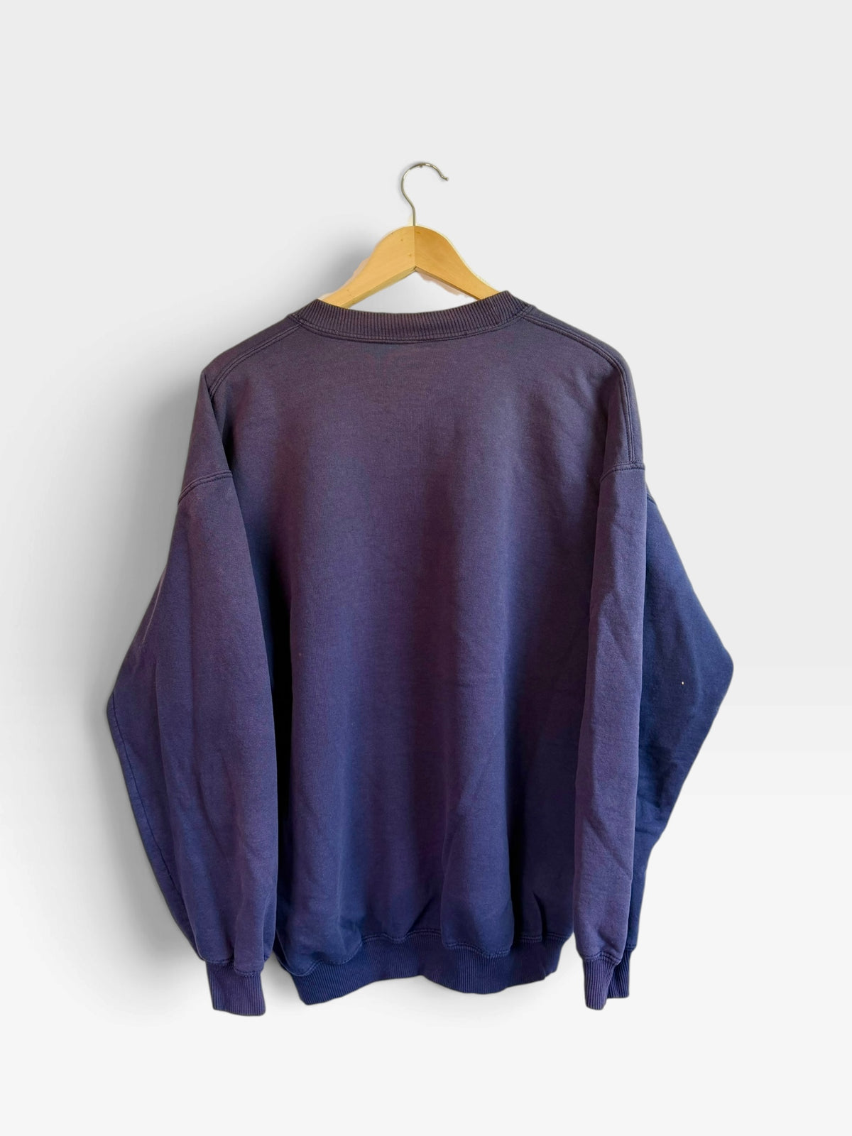 225 Threadz vintage navy blue crewneck sweatshirt with ribbed cuffs and hem, shown from the back on a hanger.