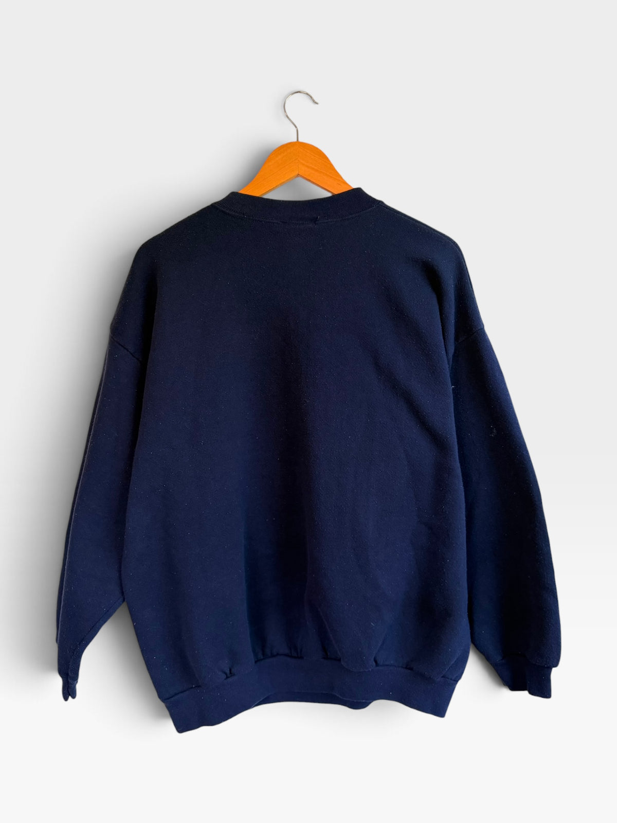 Back view of a plain navy blue 225 Threadz crewneck sweatshirt hanging on a wooden hanger against a white wall.
