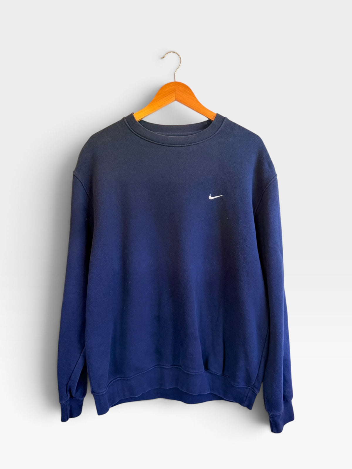 225 Threadz navy blue Nike crewneck sweatshirt with embroidered white swoosh logo on a wooden hanger