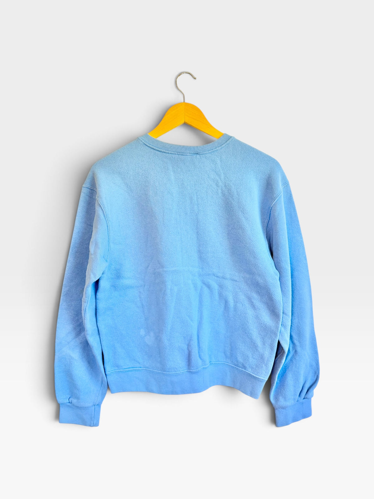 225 Threadz light blue Nike vintage crewneck sweatshirt with ribbed cuffs and hem, back view on a yellow hanger.