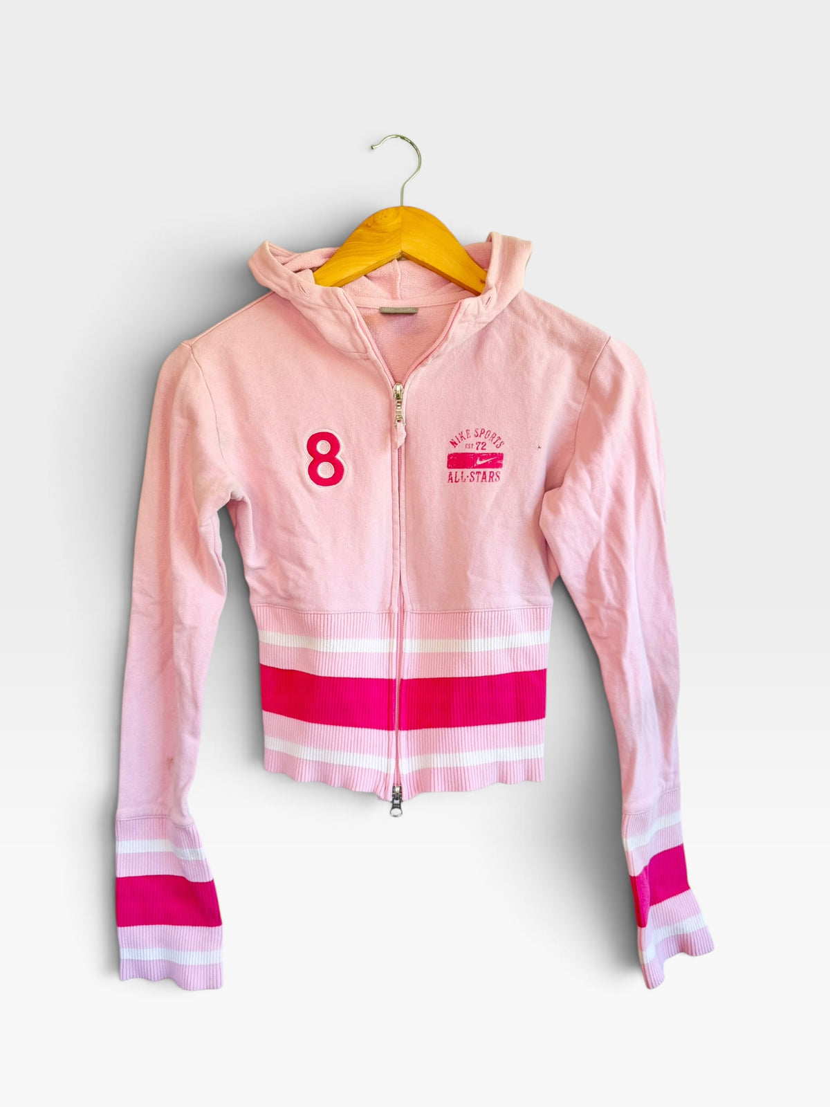 225 Threadz pastel pink Nike cropped zip-up hoodie with ribbed striped cuffs, hem, and collegiate graphic detailing.
