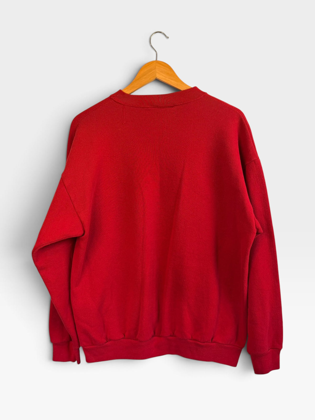 225 Threadz red crewneck sweatshirt hanging on a wooden hanger, back view showing plain solid fabric.