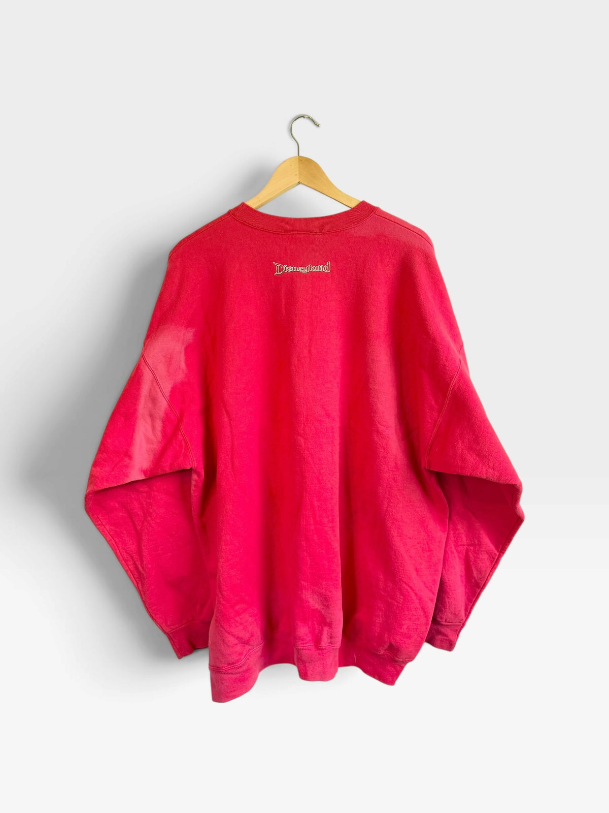 225 Threadz red vintage crewneck sweatshirt featuring a small Disneyland logo on the upper back, hanging on a hanger.