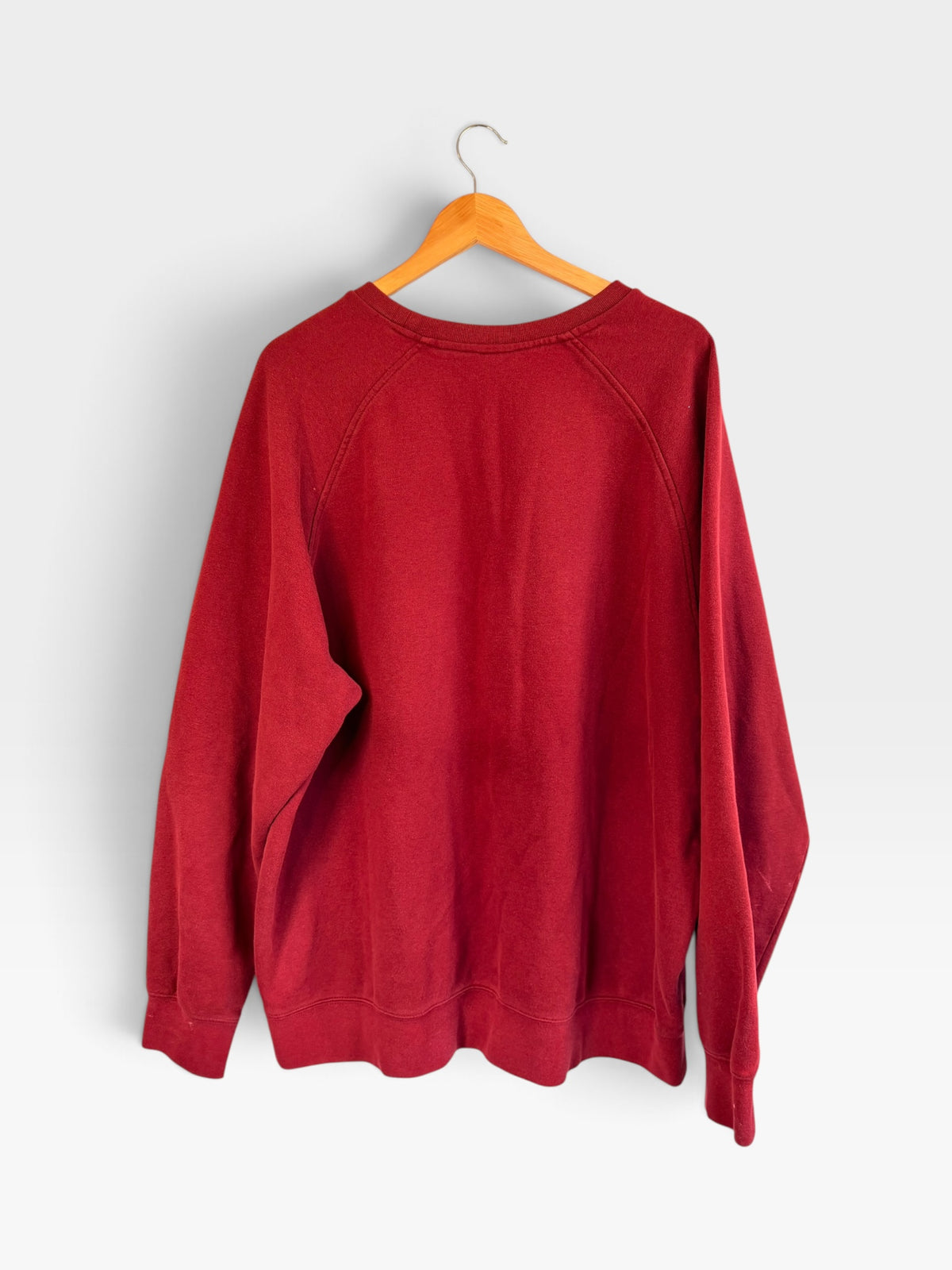225 Threadz deep red Nike crewneck pullover sweatshirt with raglan sleeves hanging on a wooden hanger