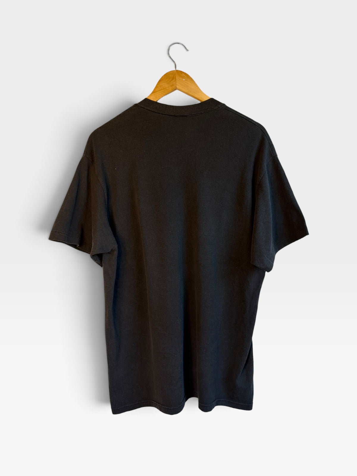 225 Threadz vintage black cotton crewneck t-shirt seen from the back on a wooden hanger against a white wall.