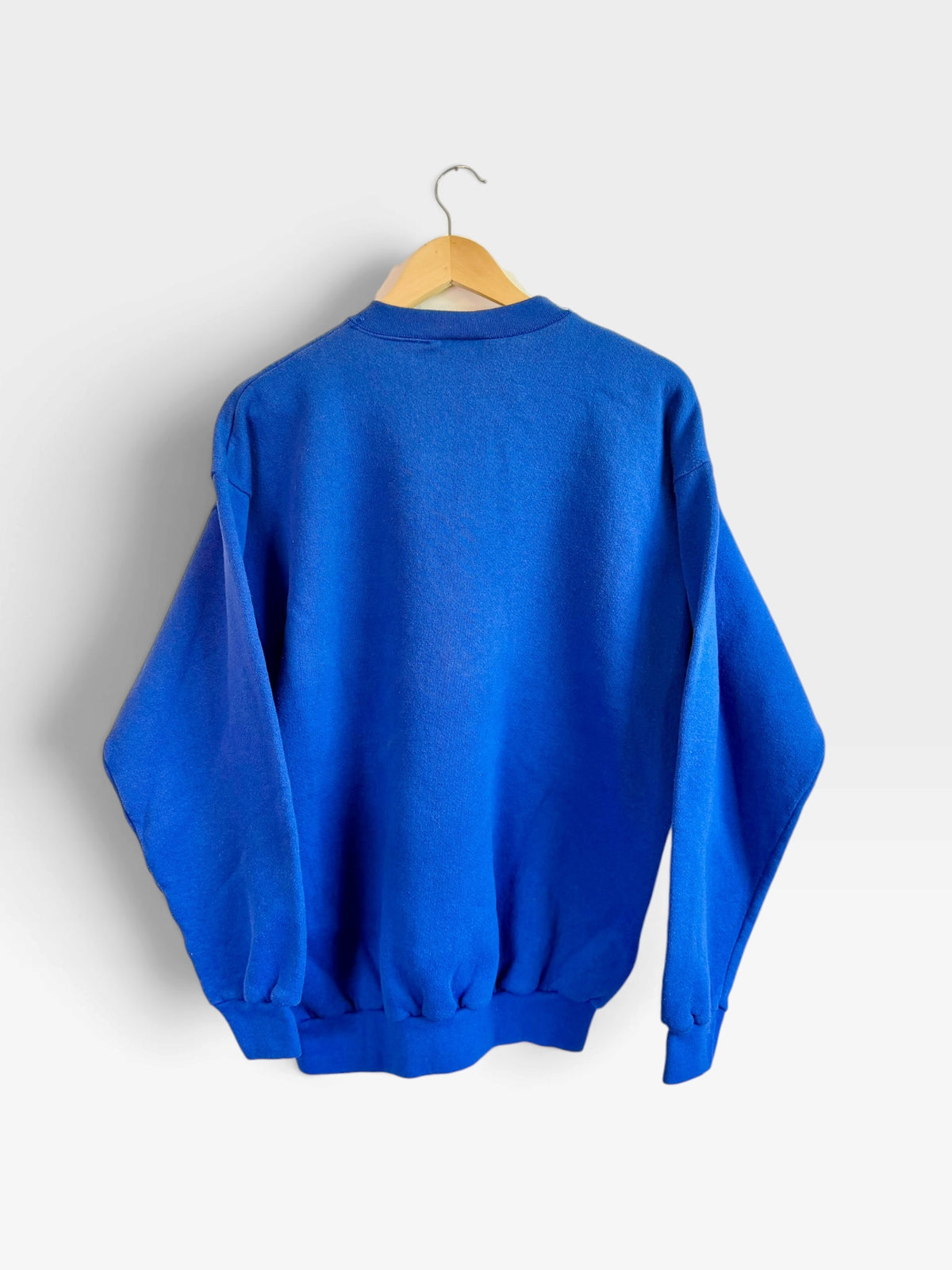 Back view of a 225 Threadz vintage blue St. Louis Rams crewneck sweatshirt hanging on a wooden hanger.